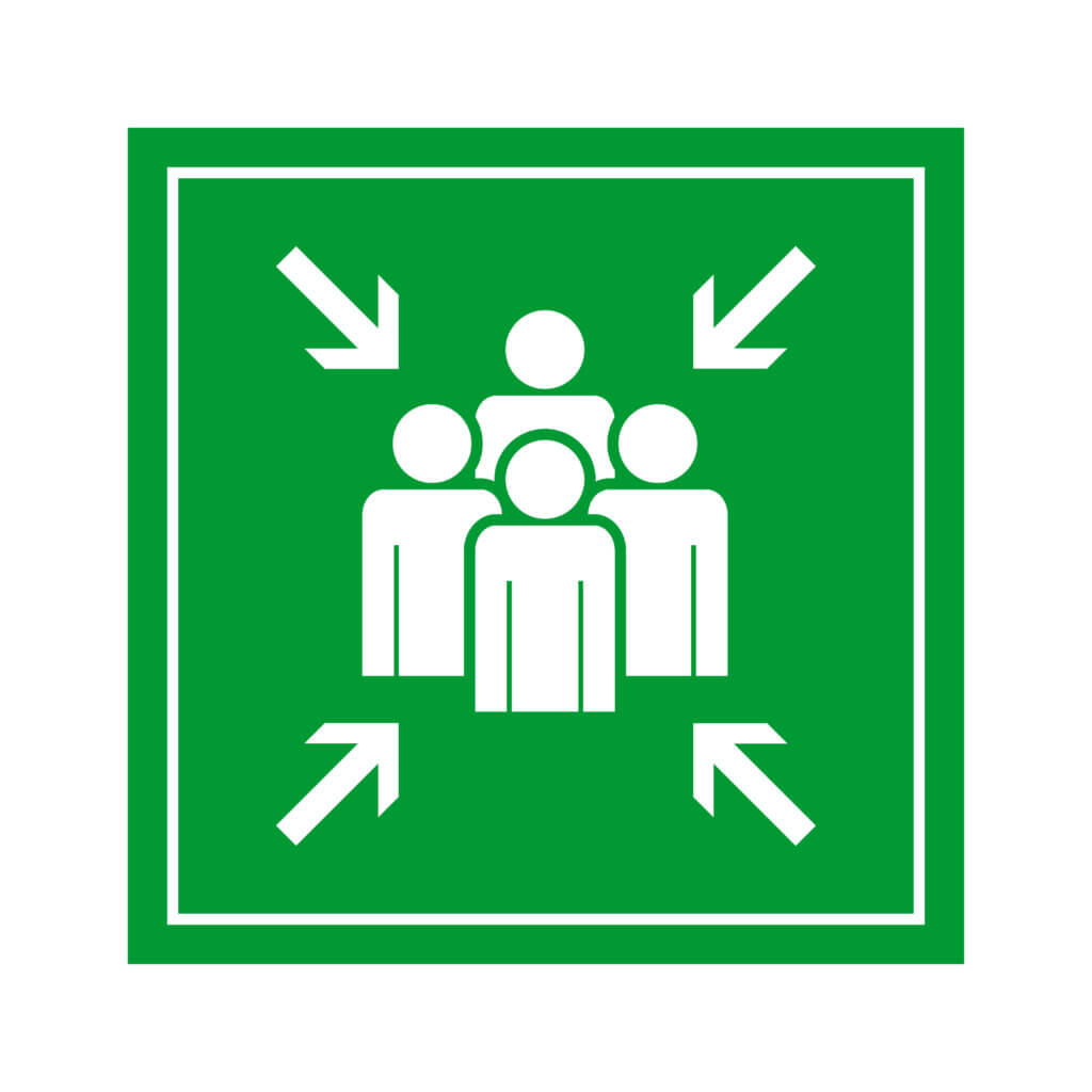Een groen vierkant bord met vier witte stokfiguren in het midden en vier witte pijlen die vanuit elke hoek naar binnen wijzen. Deze markeren een verzamelpunt met vier tips voor een snelle en veilige ontruiming.